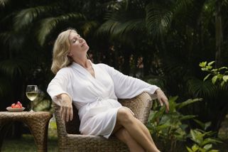 mujer en albornoz relajándose, respirando el aire limpio
